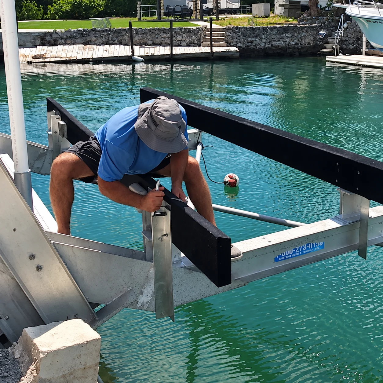 A worker adjusting boat lift bunks beside the dock